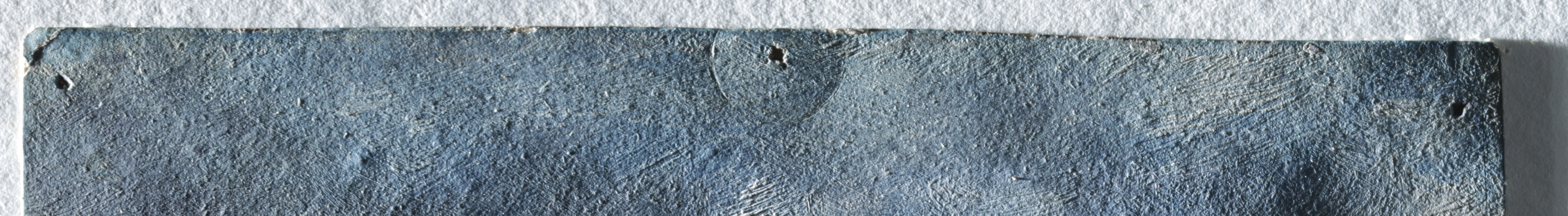 A magnified pin hole with a circular indentation surrounding it in the top edge of a skyscape sketch