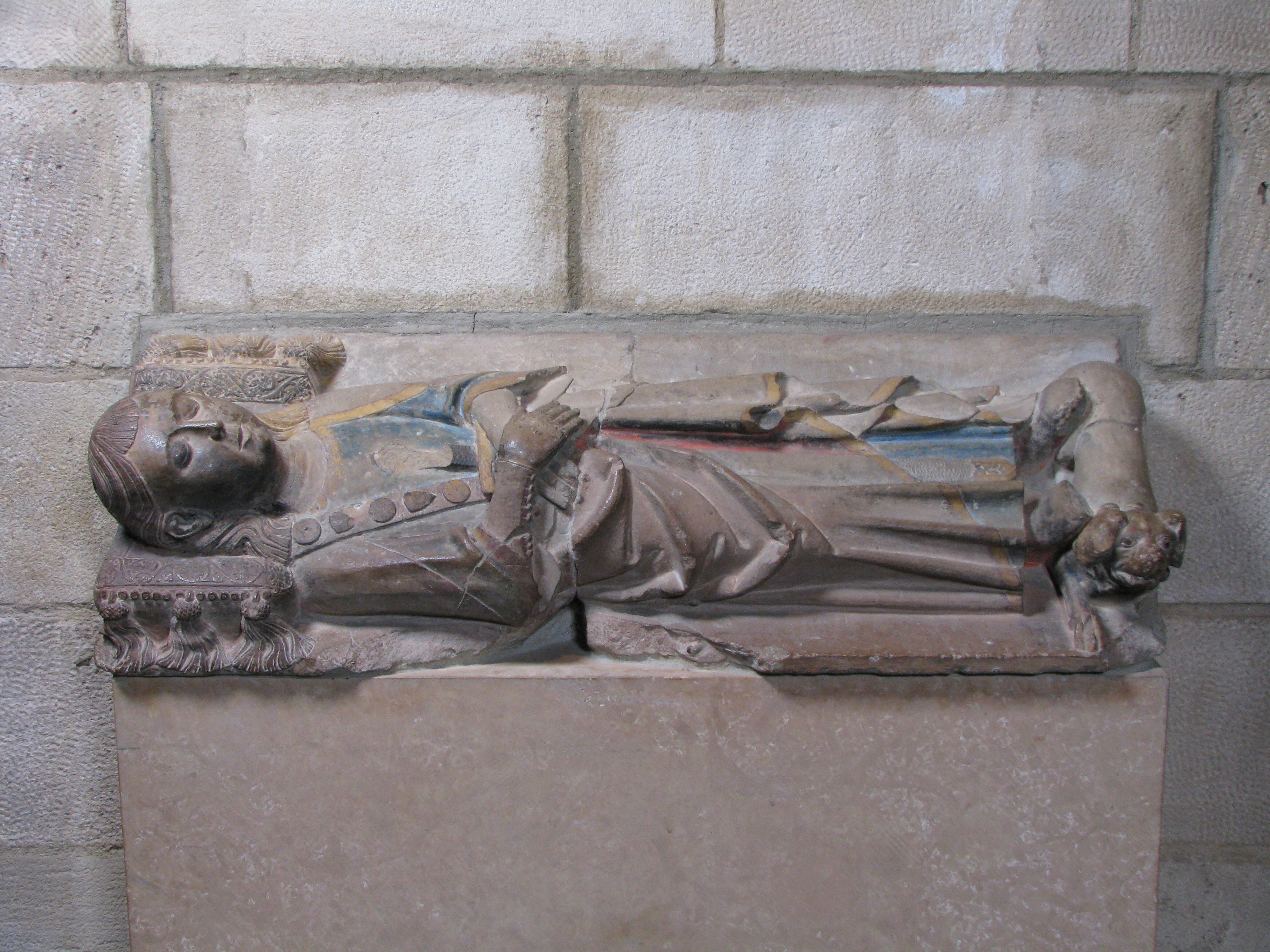 Tomb effigy of a boy with hands crossed over his chest, and a dog at his feet. The ensemble is carved in limestone with polychromy.