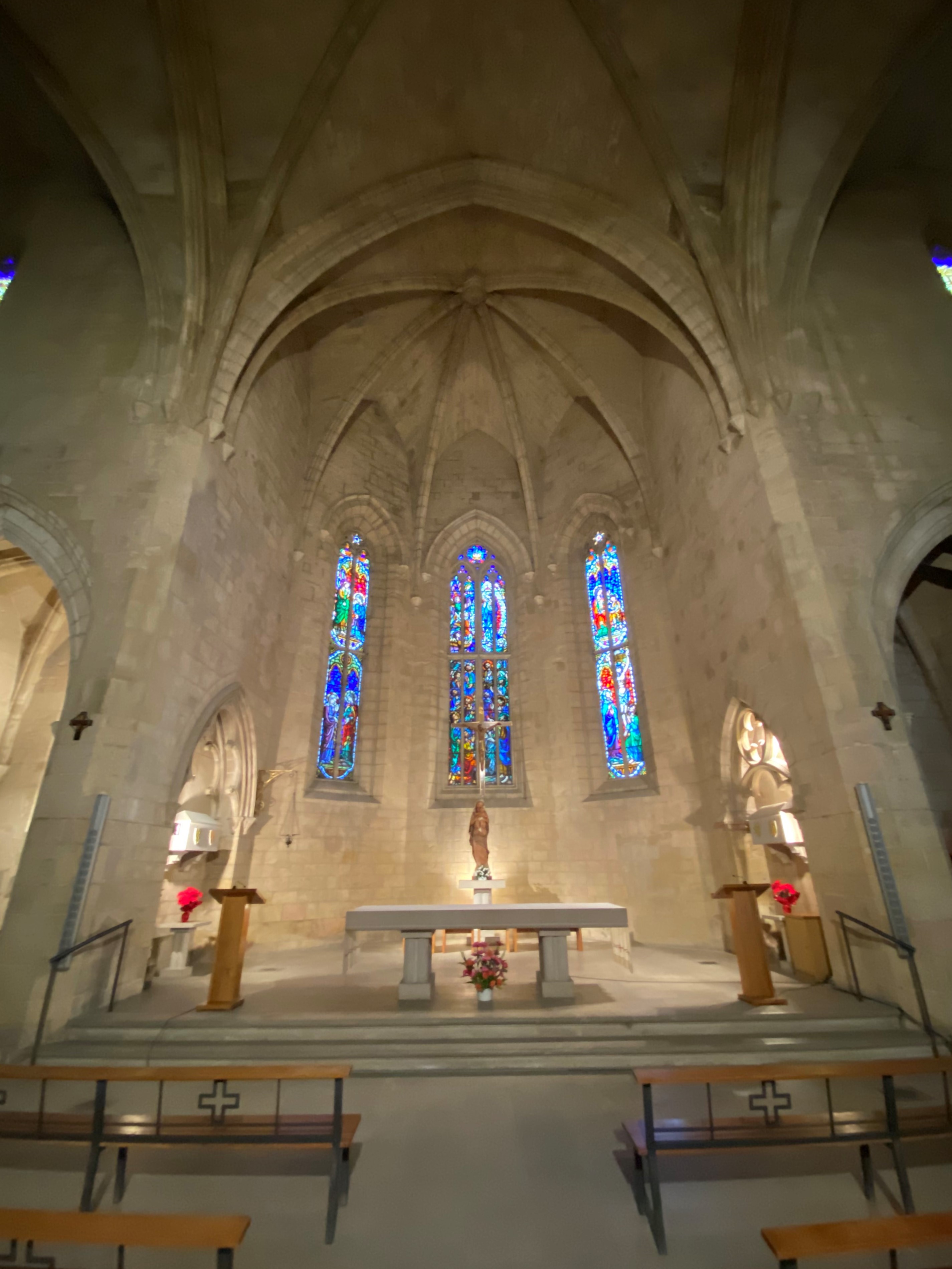 Interior of a gothic church with modern stone caskets in the niches to the left and right of the presbytery.