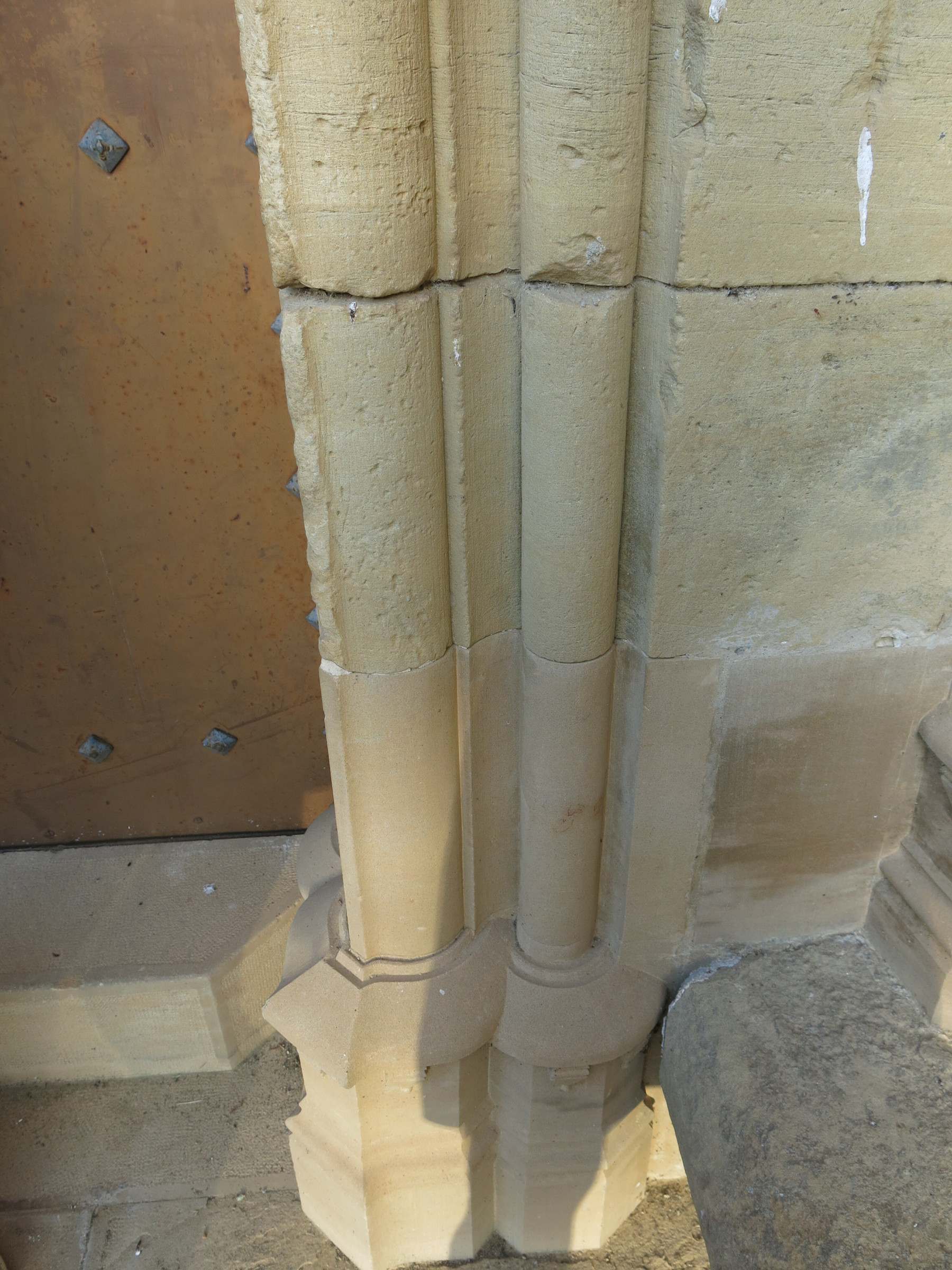 Modern stone replacements on the bottom archway jambs of the stone gothic doorway.