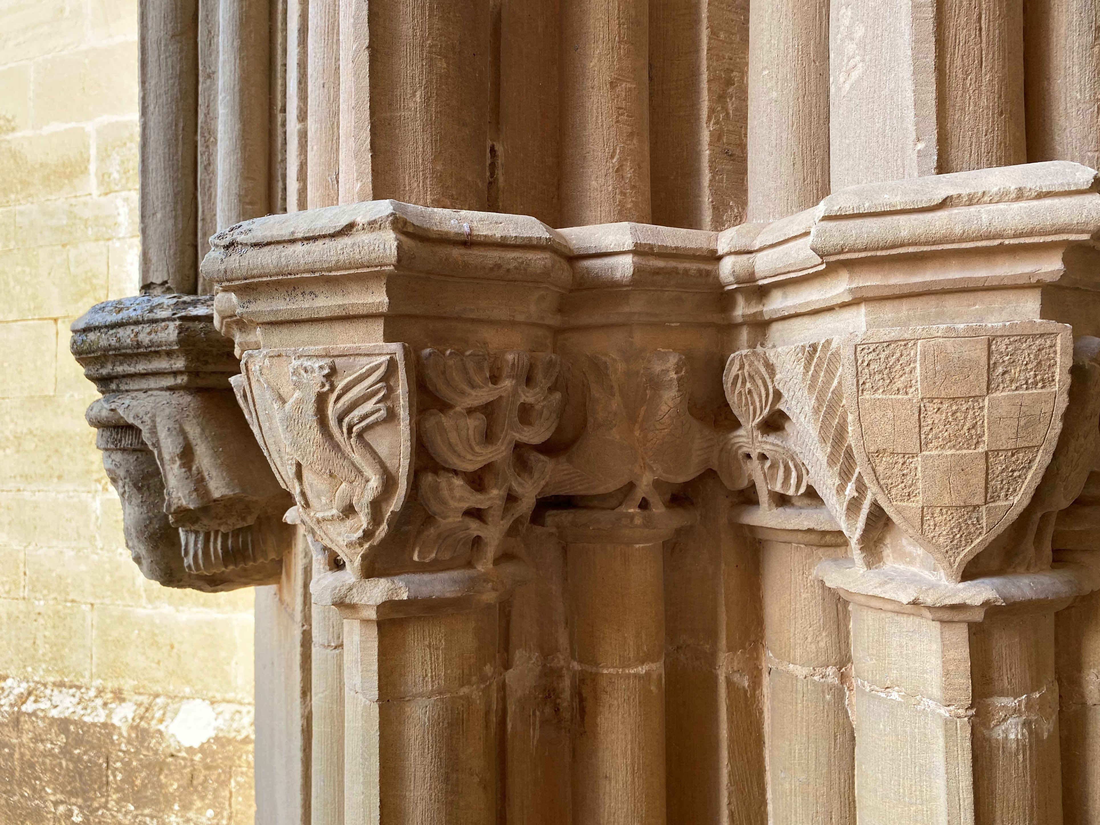 Series of stone capitals with a lion rampant, an intertwined dove and a shield with coat of arms.