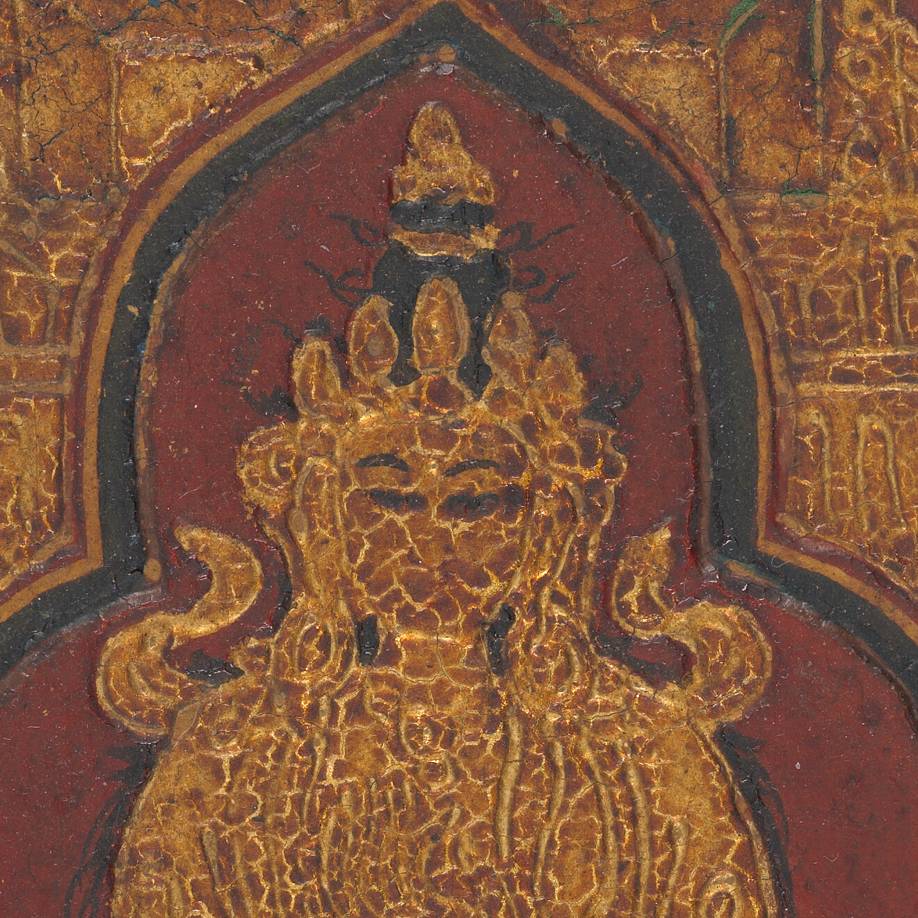 Close up of gilded face with cracked dark orange-brown coating obscuring the details of the figure.